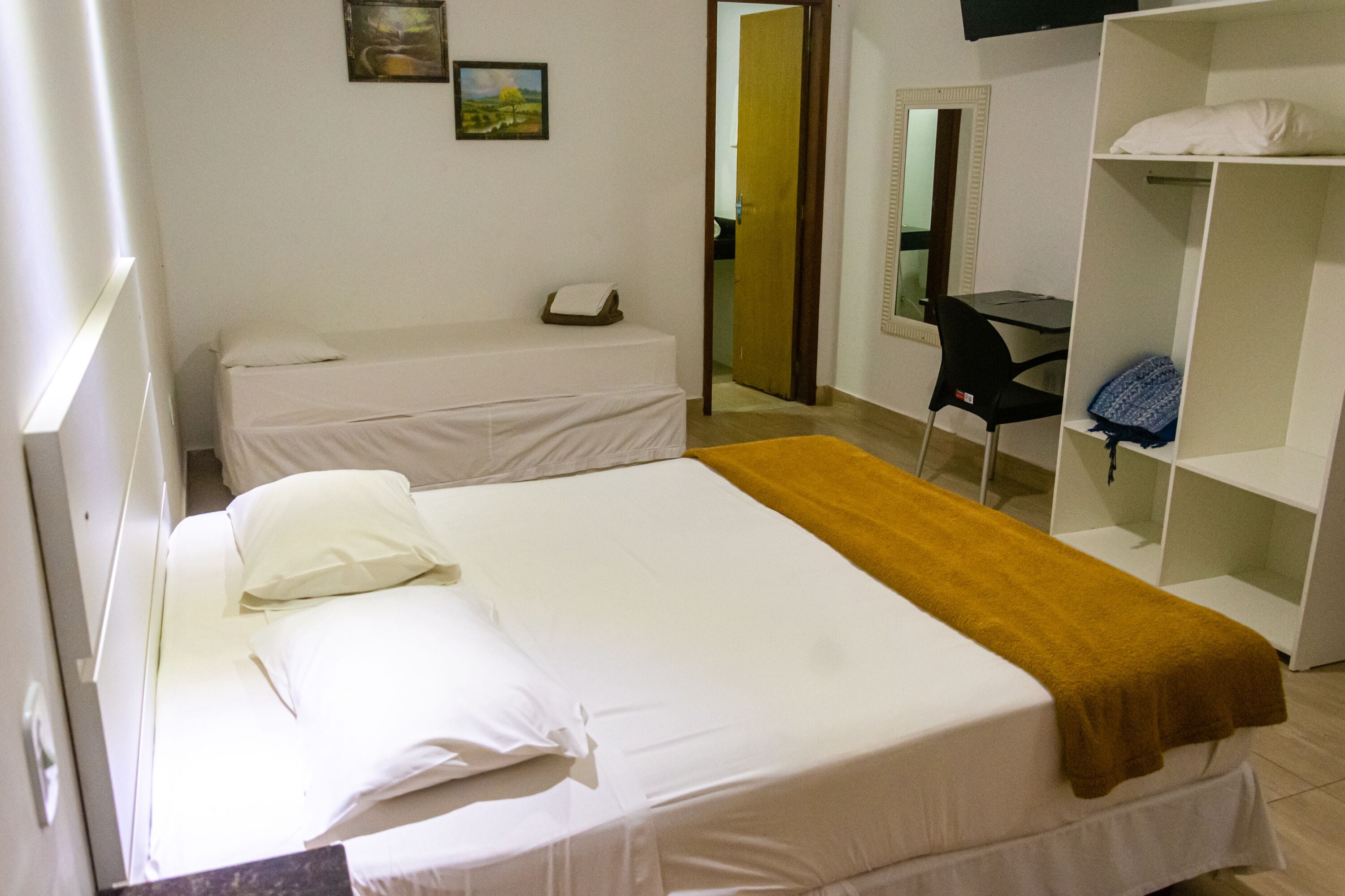 A hotel room with a bed, a desk, a chair, and a wardrobe.
