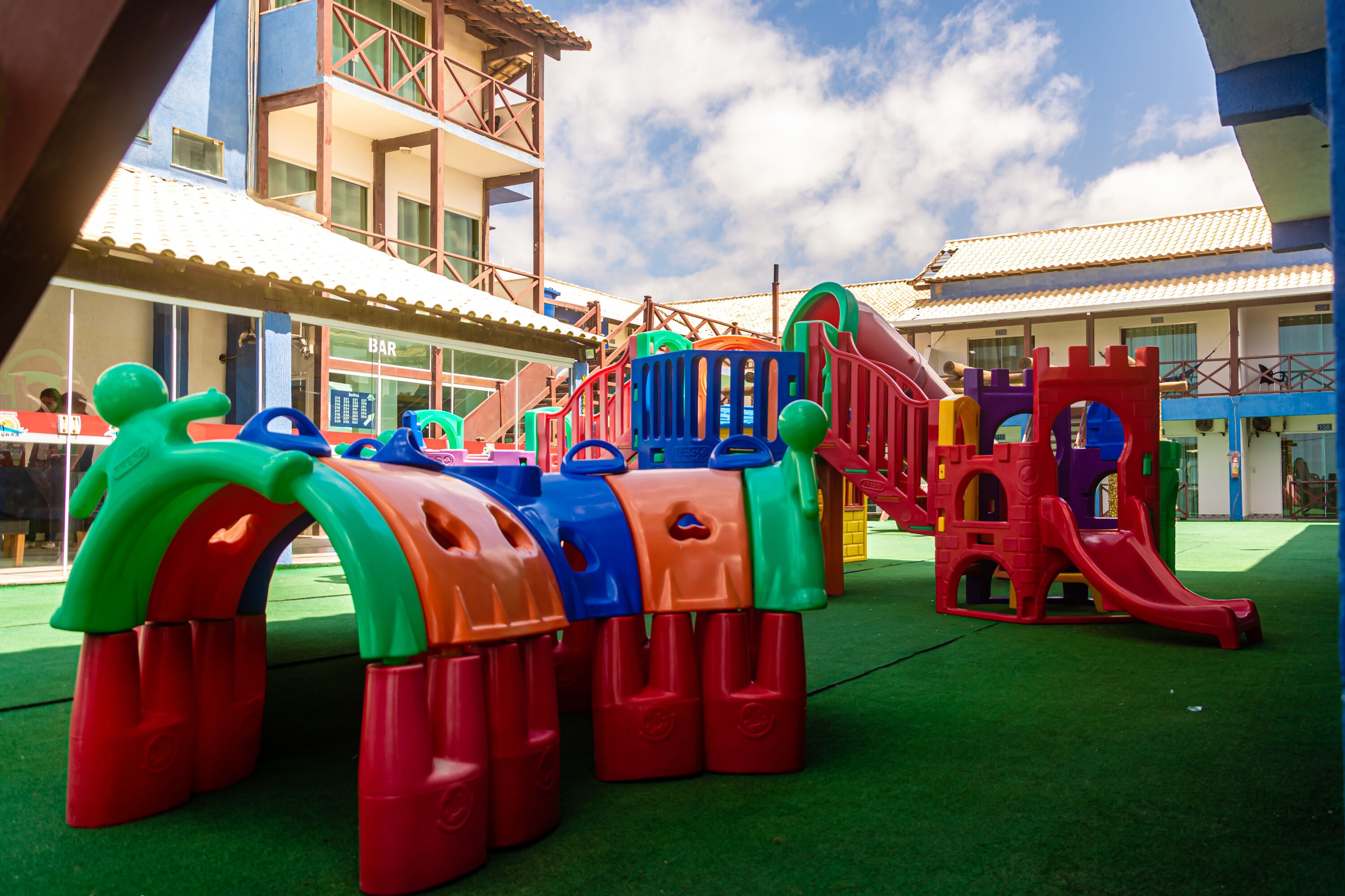 A children's play area with colorful structures and a building in the background.