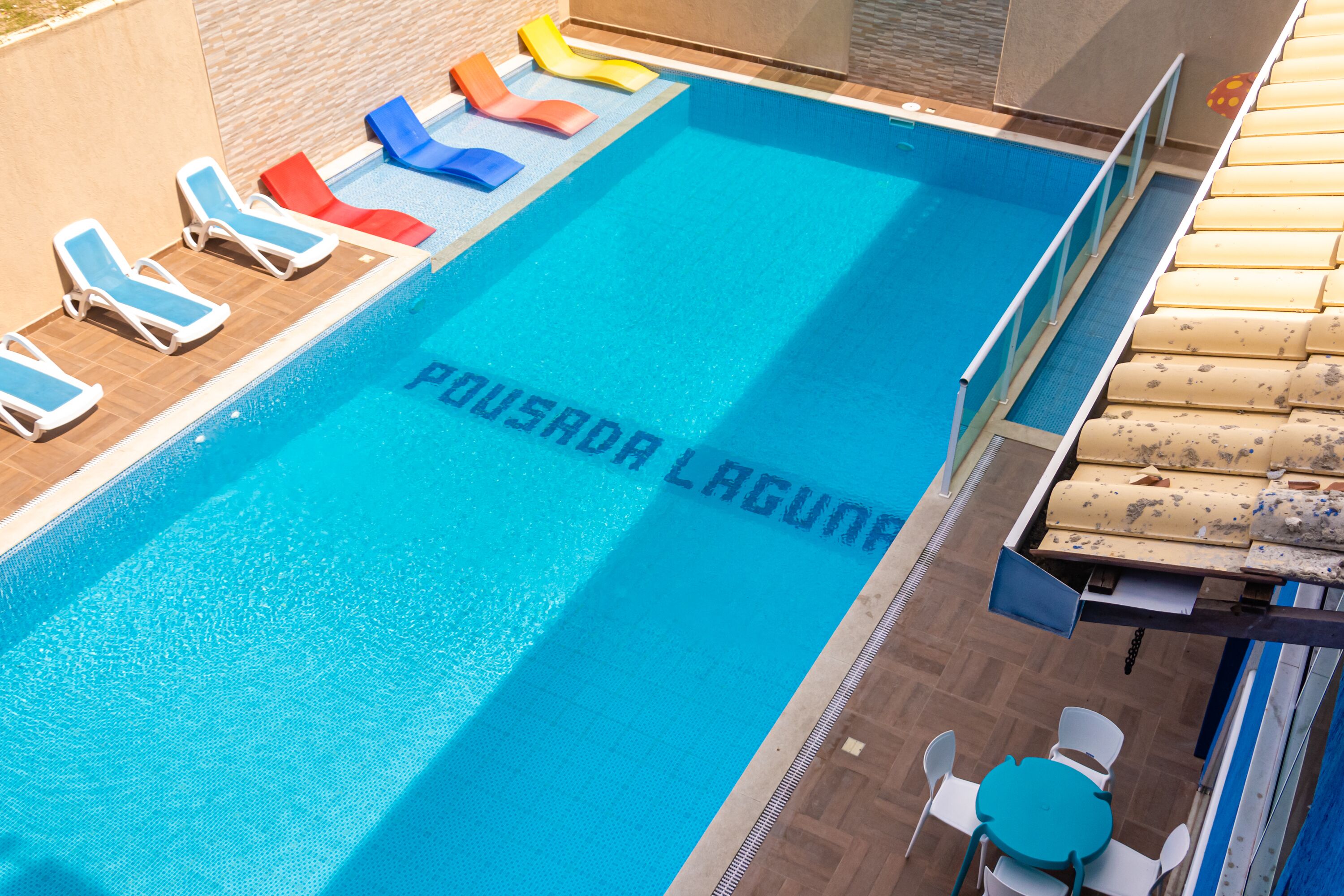 Una piscina con sillas de descanso y una mesa.