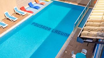 Una piscina con sillas de descanso y una mesa.