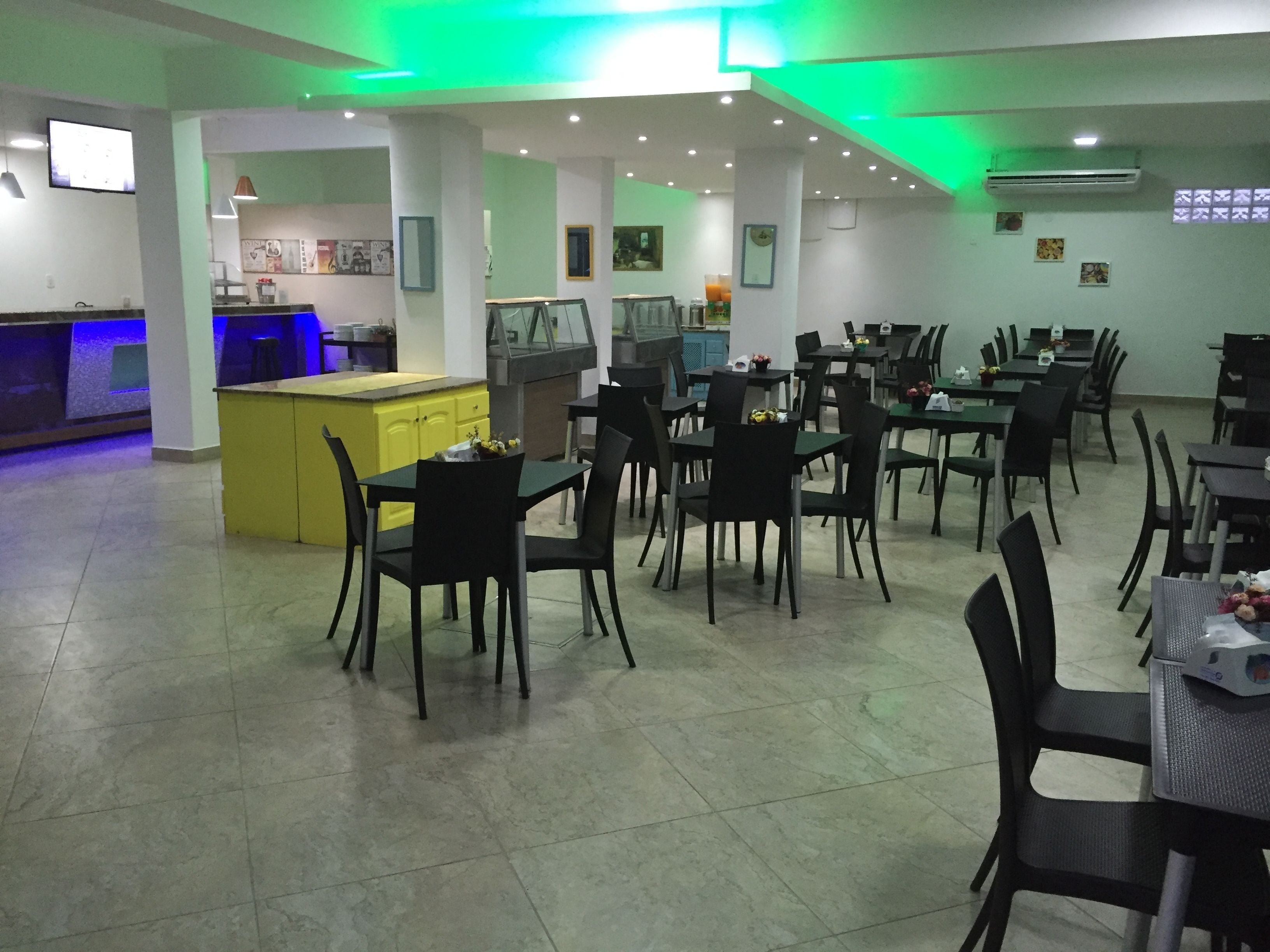Un ristorante con diversi tavoli e sedie, una zona cucina e un bancone bar.