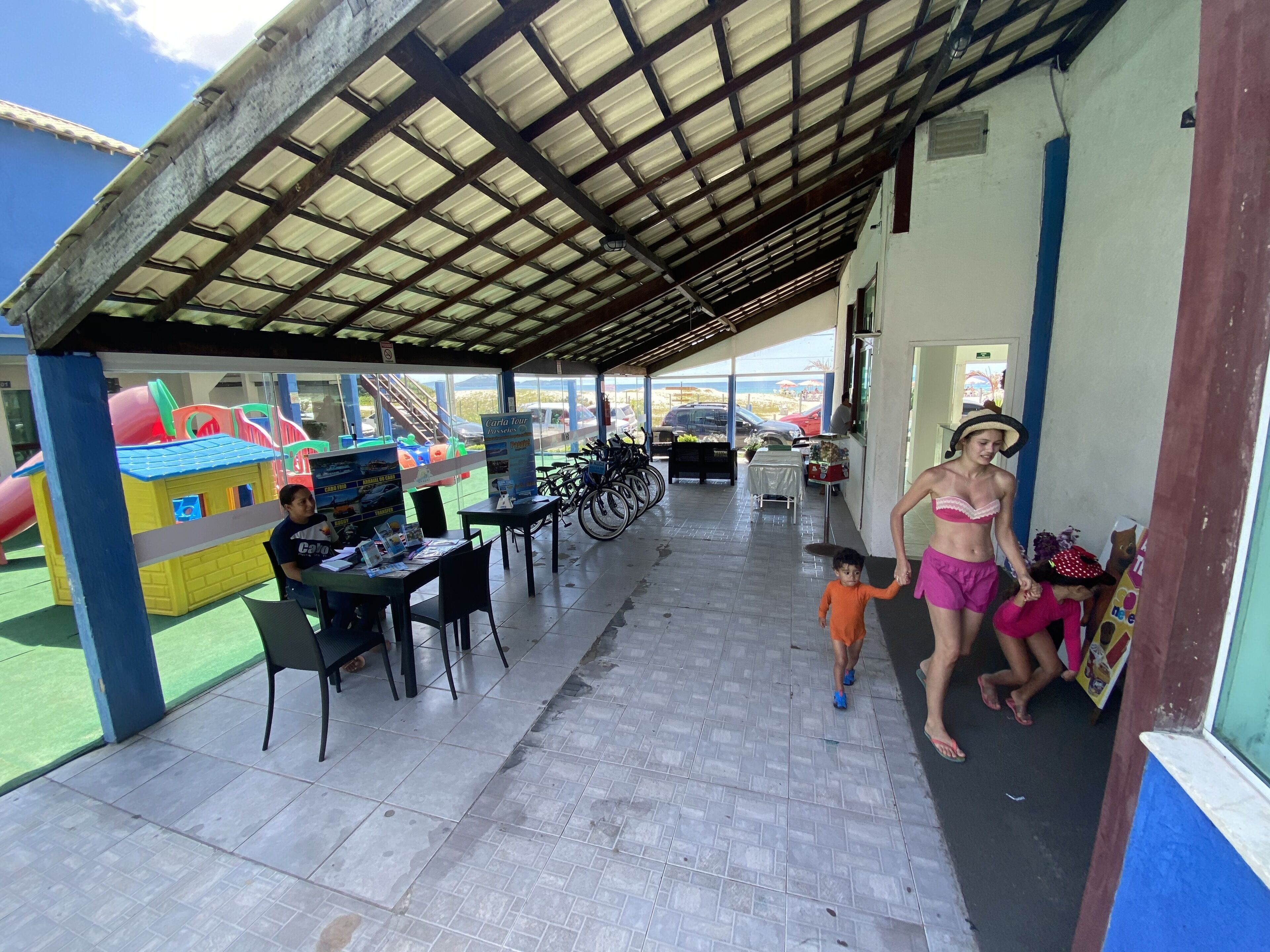 An outdoor covered area with a play structure, tables, chairs, and bicycles.