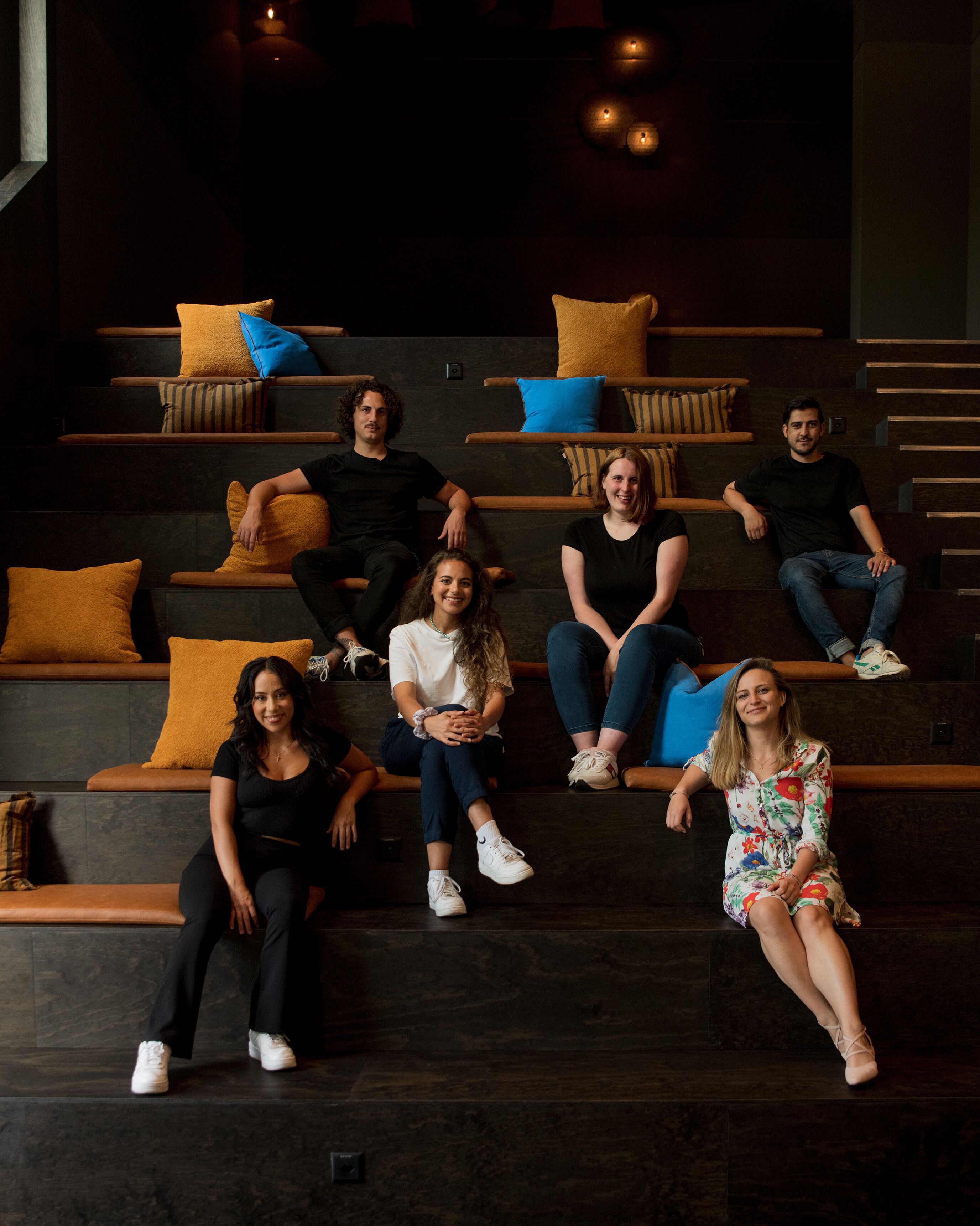 Un grupo de personas sentadas en una escalera de madera con cojines.