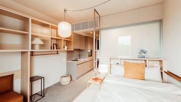 Una habitación de hotel moderna con una cama, mesita de noche, lámpara y vistas de la ciudad.