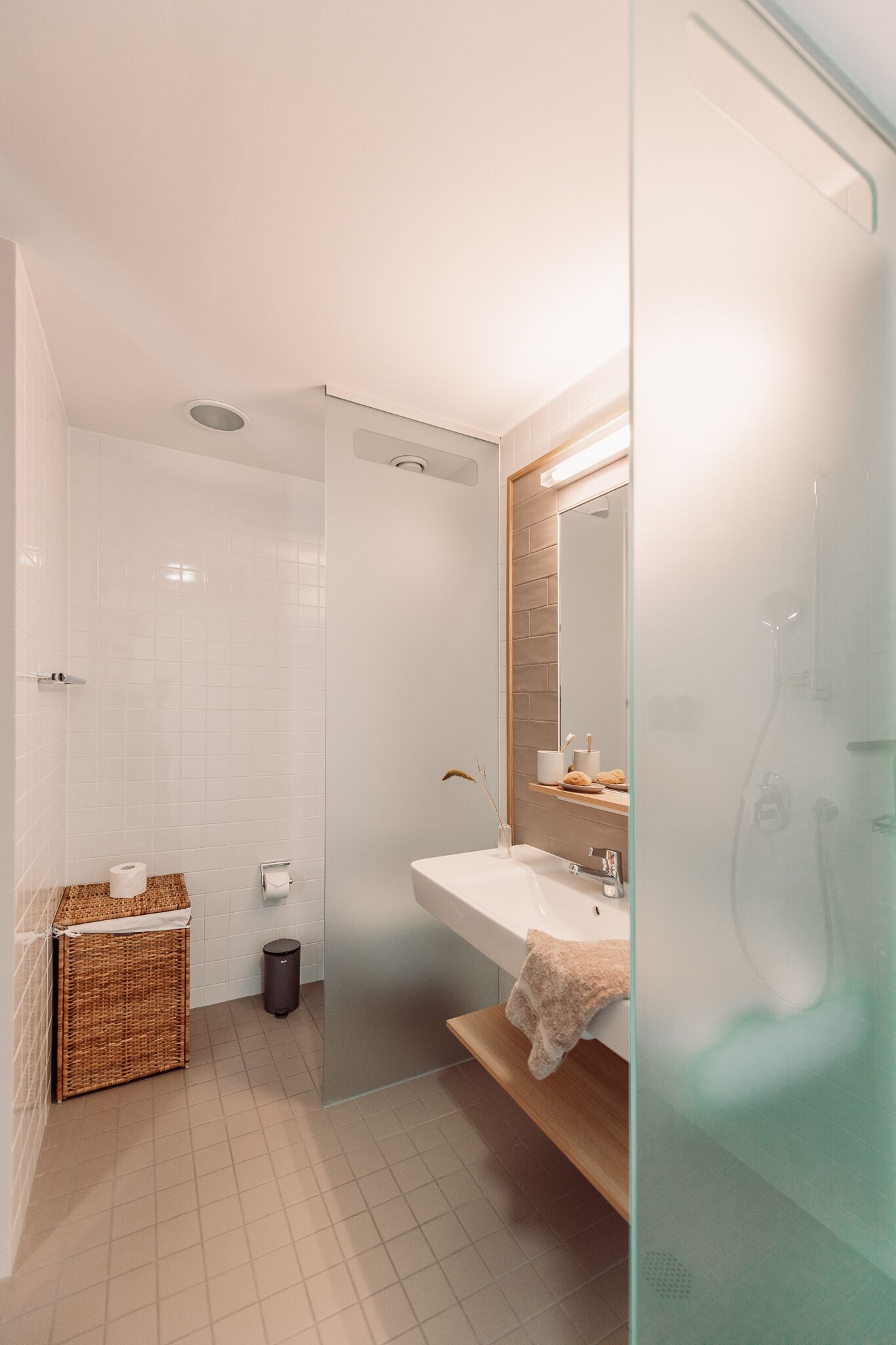 Un baño moderno con cabina de ducha de vidrio, un lavamanos blanco y un espejo sobre él.