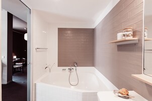Un baño moderno con una bañera independiente, un perchero y un estante con artículos de aseo.
