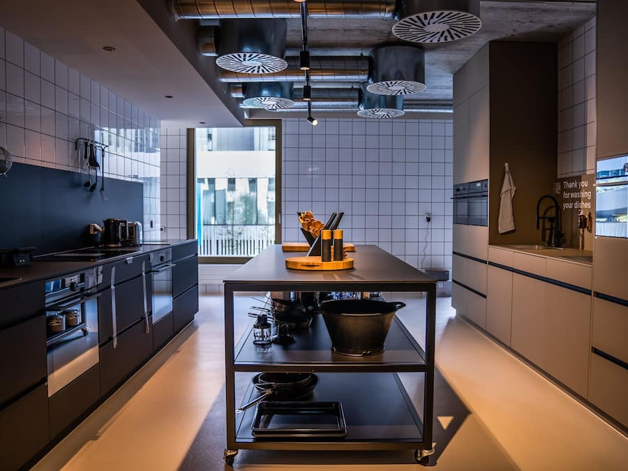 Una cocina moderna con una isla central, electrodomésticos de acero inoxidable y vistas al exterior.