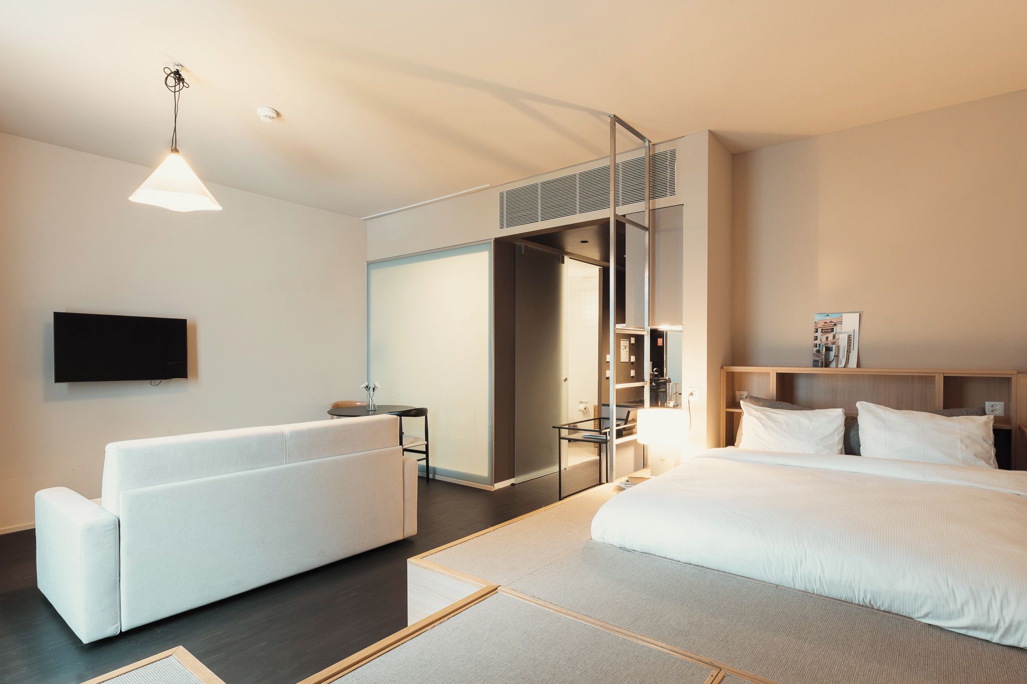 Une chambre d’hôtel moderne équipée d’un lit, d’un canapé, d’une télévision et d’un bureau.