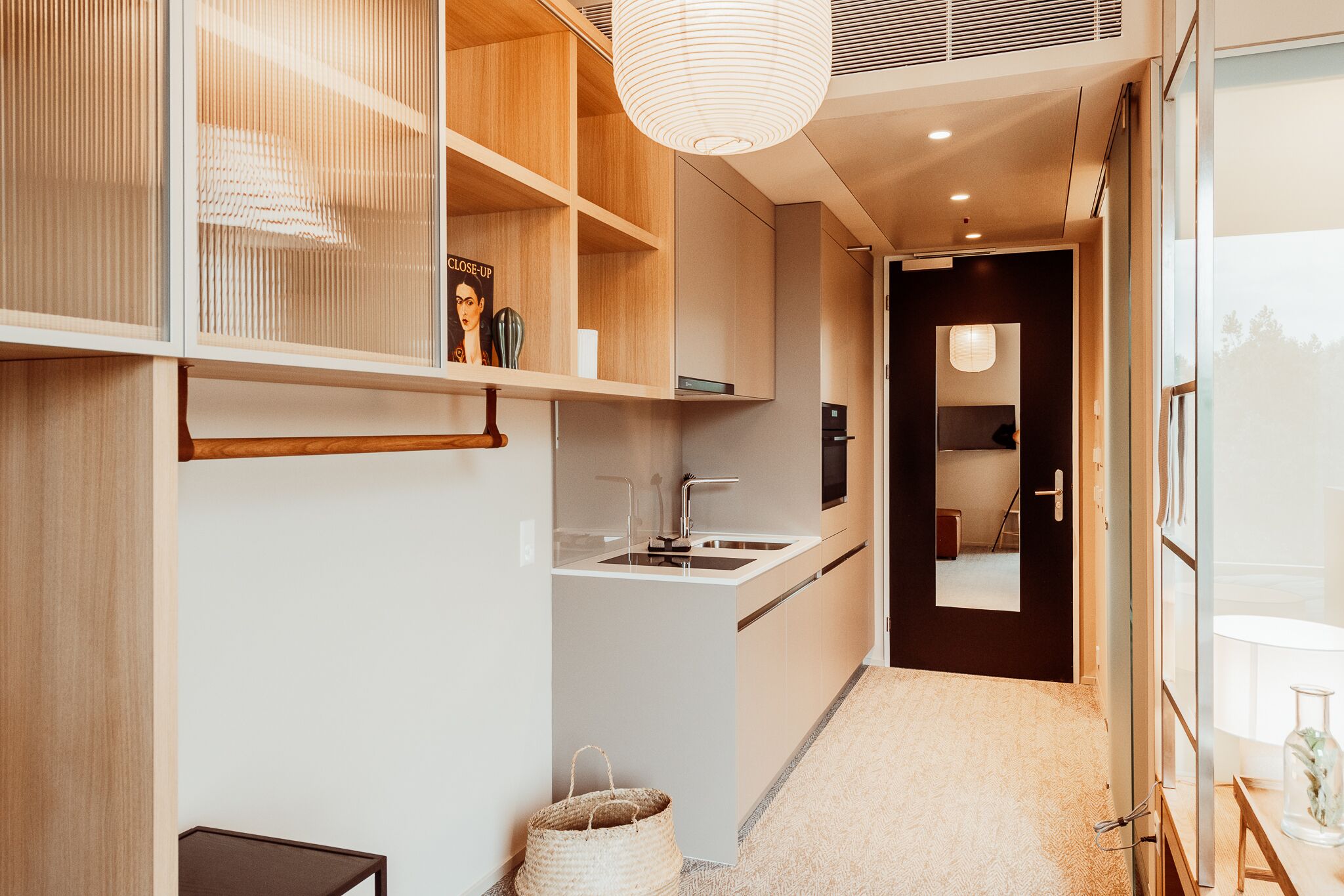 Une cuisine moderne avec des meubles blancs, un évier encastré et un luminaire suspendu.