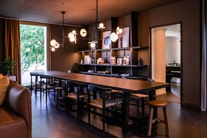 A modern kitchen with a long dining table, bar stools, and pendant lighting. - City Pop 2Night Basel - Self check-in (Basel)