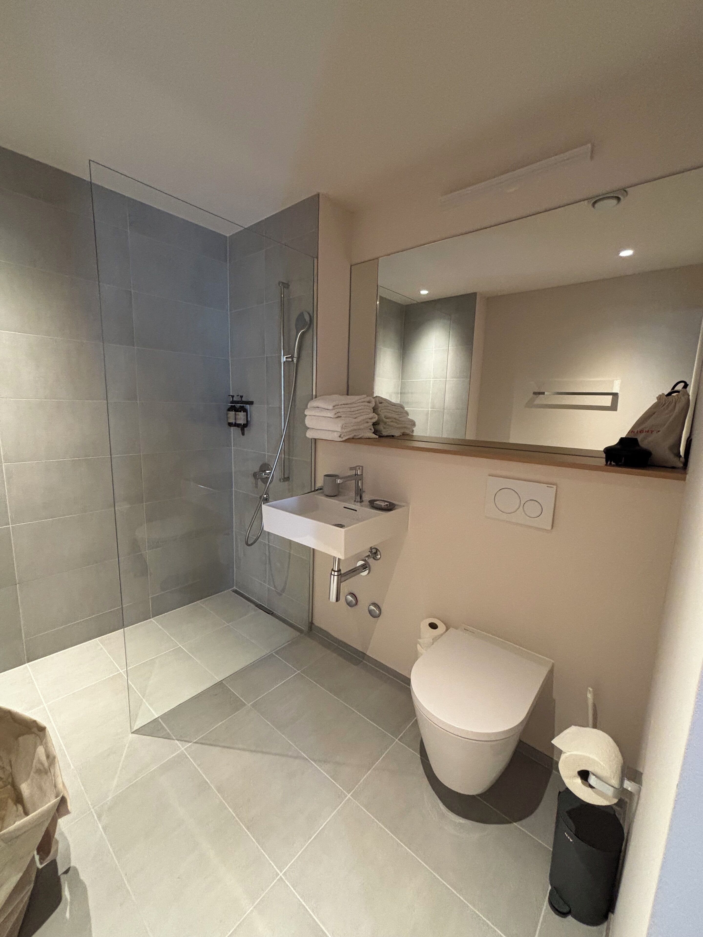 Une salle de bain moderne avec une douche à parois de verre, un lavabo blanc, des toilettes et un miroir au-dessus du lavabo.