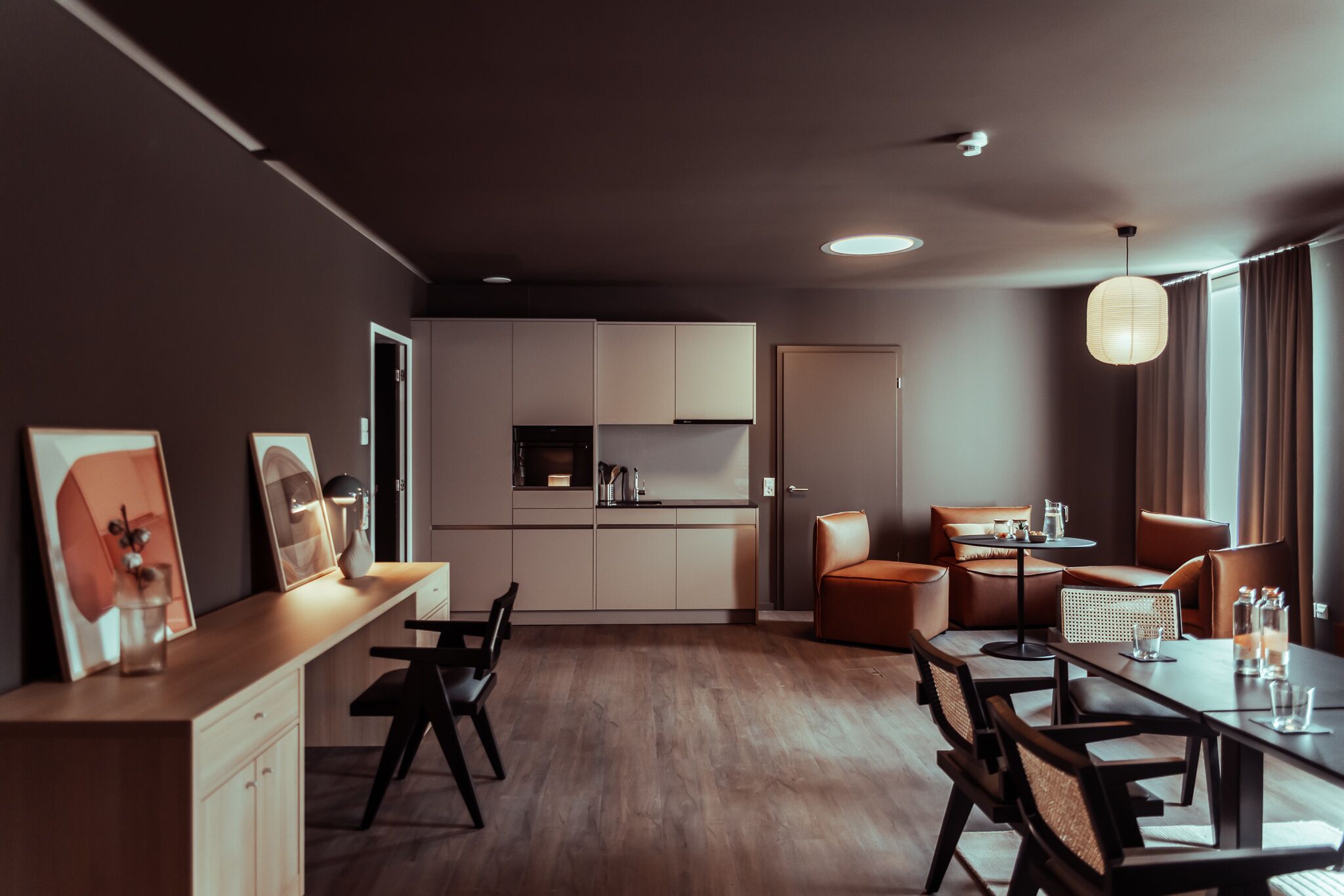 Una sala de estar moderna con comedor, cocina y un amplio ventanal con cortinas.