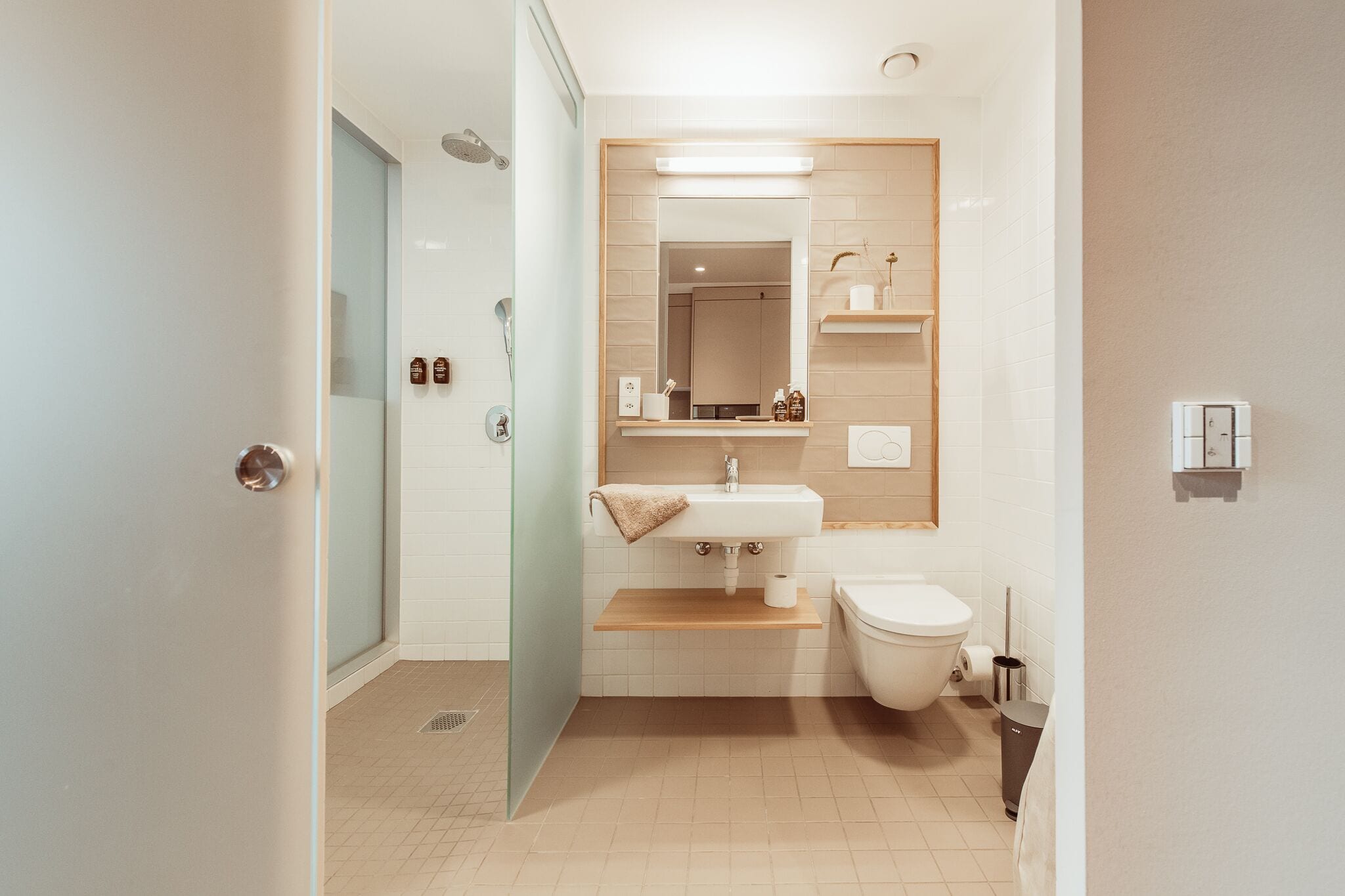 Een moderne badkamer met een glazen douchecabine, een wastafel met spiegel erboven en een toilet.