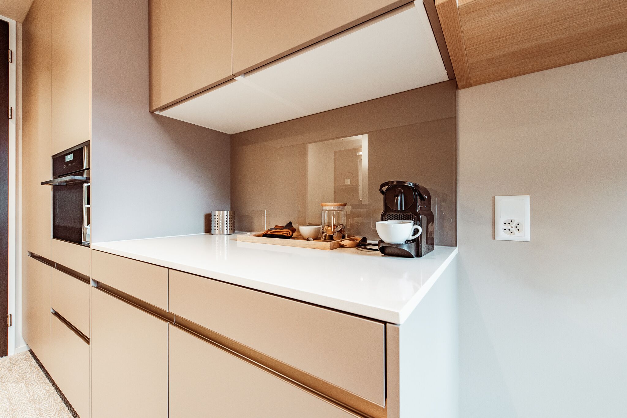 Une cuisine moderne avec un plan de travail blanc, des appareils électroménagers intégrés et un design épuré.