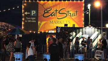 Un cartel publicitario de EatStreet Markets con un cajero automático y señal de estacionamiento.