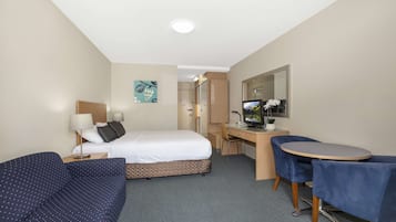 Et hotelværelse med seng, skrivebord, stol og et lille bord.