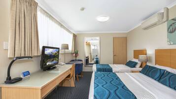 Une chambre d’hôtel avec deux lits, un bureau équipé d’un ordinateur, une chaise et une lampe de bureau.