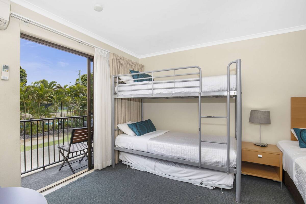 Een hotelkamer met balkon, een bed, nachtkastje en stoel.