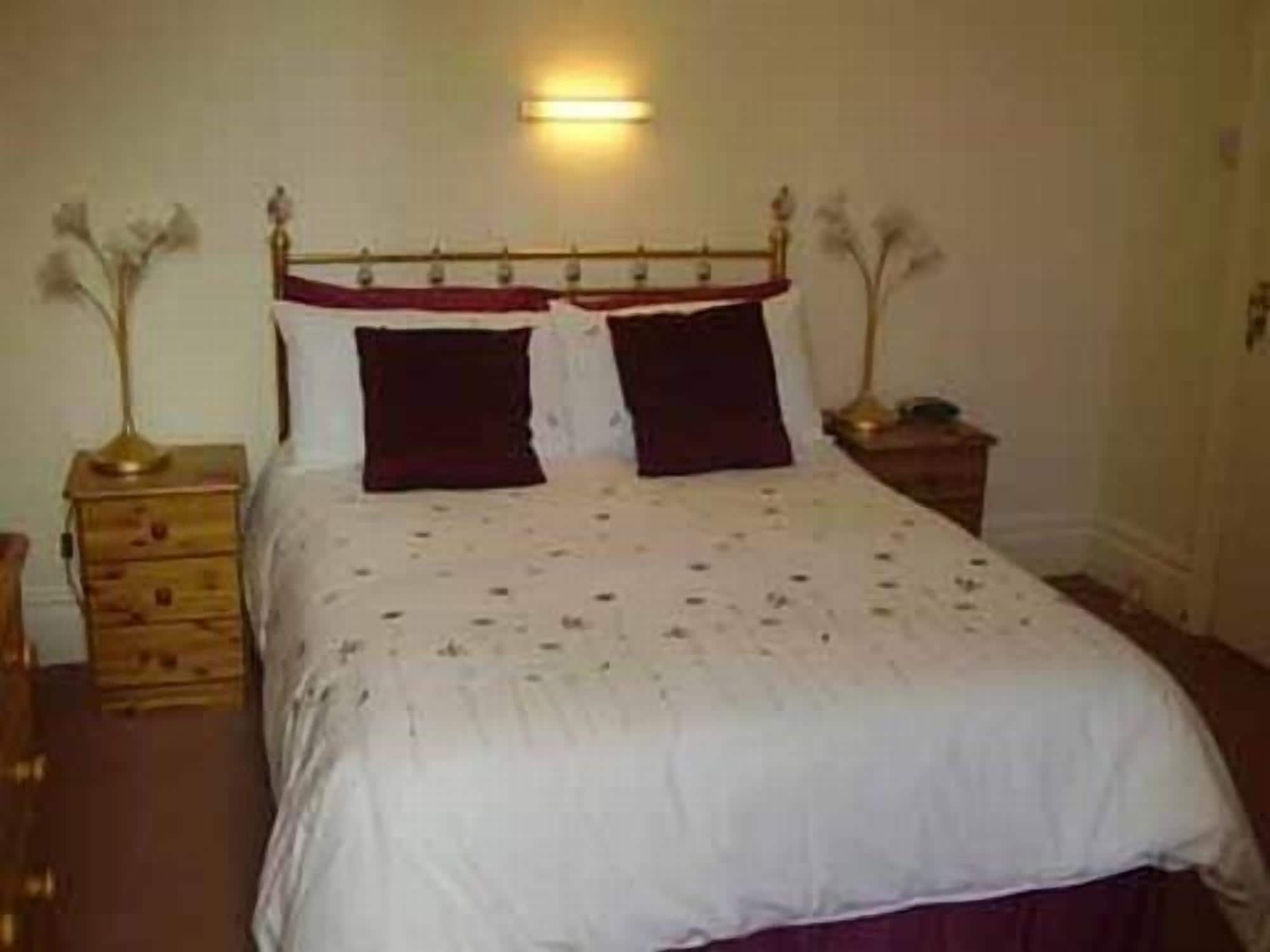 A bedroom with a bed, two bedside tables, and a wall-mounted light fixture.