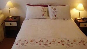 A hotel room with a bed, two bedside tables, and two lamps.