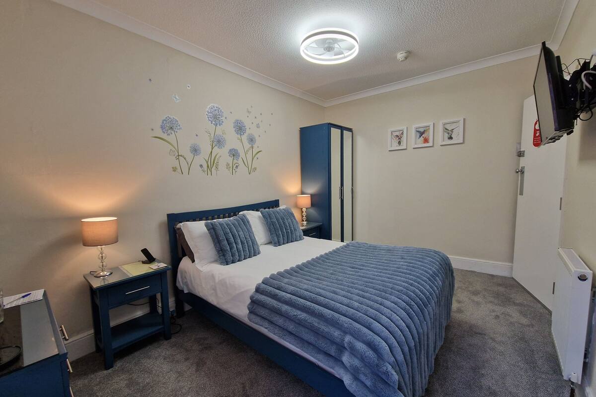 A bedroom with a bed, two bedside tables, a wardrobe, and a ceiling light.