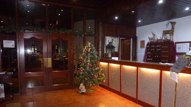 A reception area with a Christmas tree, wooden reception desk, and a sign indicating a restaurant. -  Hotel Pantanha Nature & Fitness (Nelas)
