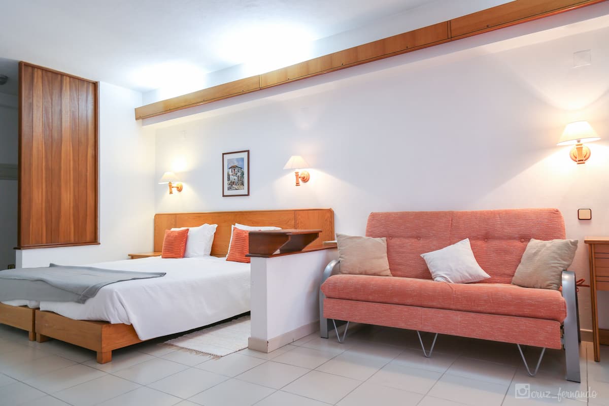 Ein modernes Schlafzimmer mit zwei Betten, einer Schlafcouch und Wandlampen.