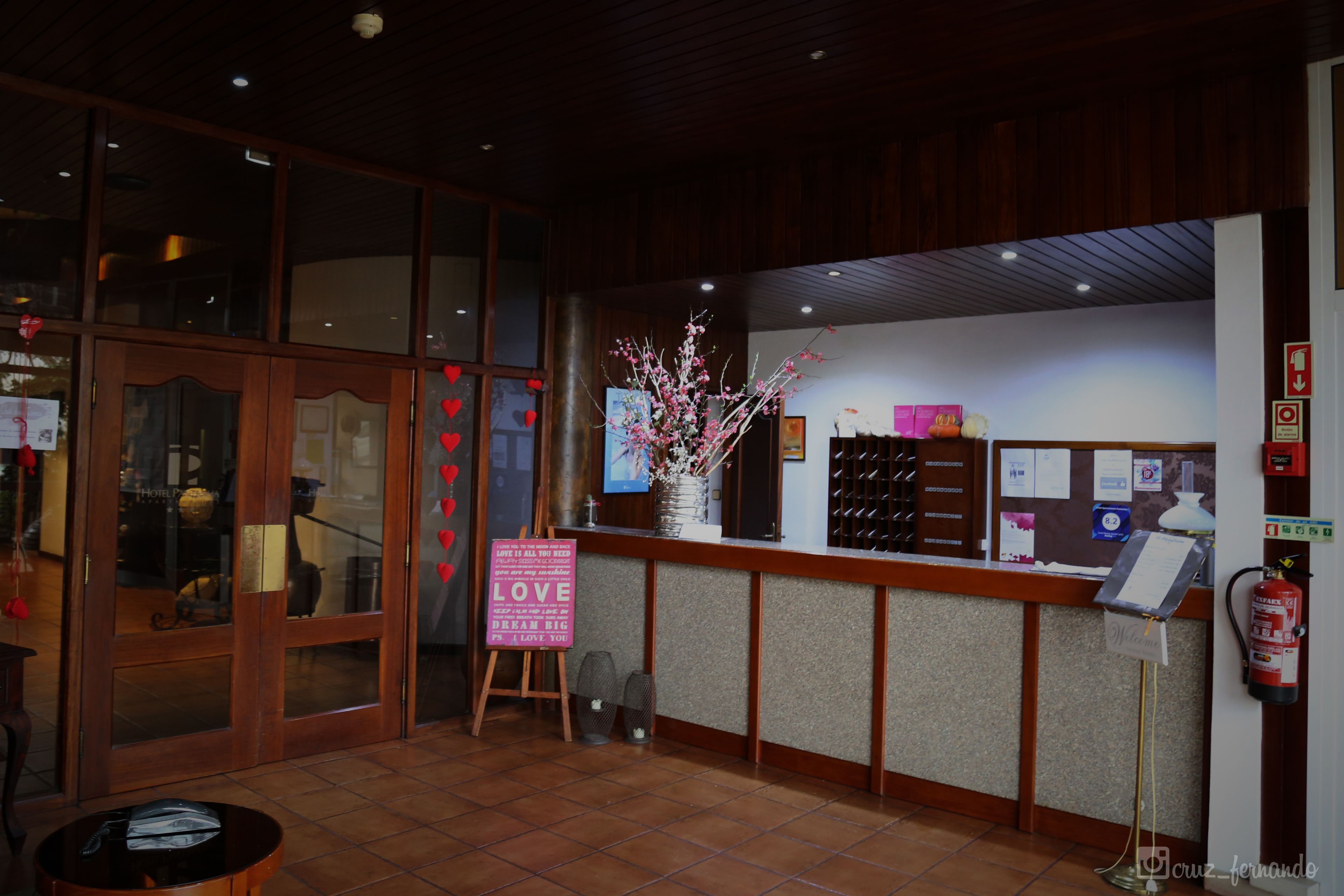 A reception area with a wooden counter, a fire extinguisher, and a sign that says "LOVE IS ALL YOU NEED."