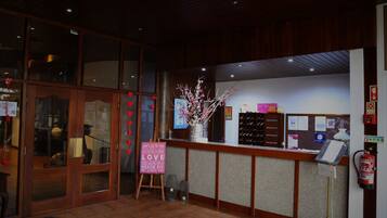 A reception area with a wooden counter, a fire extinguisher, and a sign that says "LOVE IS ALL YOU NEED."