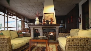 A cozy living room with wicker furniture, a fireplace, and a large window.