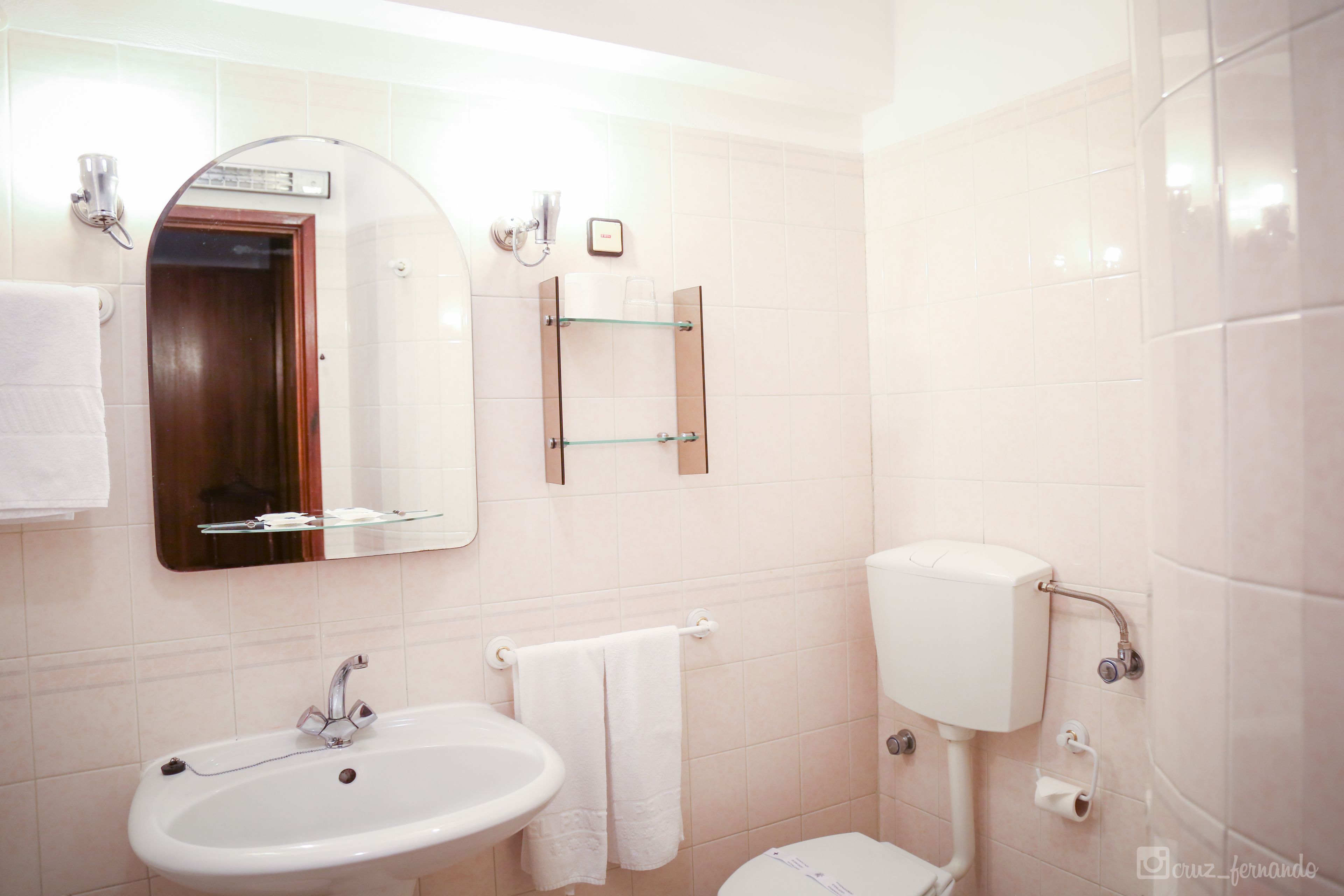 A bathroom with a white sink, a mirror, a toilet, and a towel rack.
