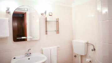 A bathroom with a white sink, a mirror, a toilet, and a towel rack.
