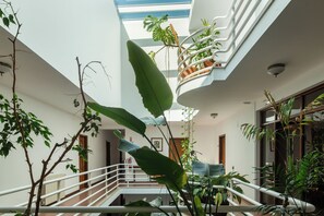 A multi-level atrium with a central staircase, surrounded by various indoor plants and a glass ceiling. -  Hotel Pantanha Nature & Fitness (Nelas)