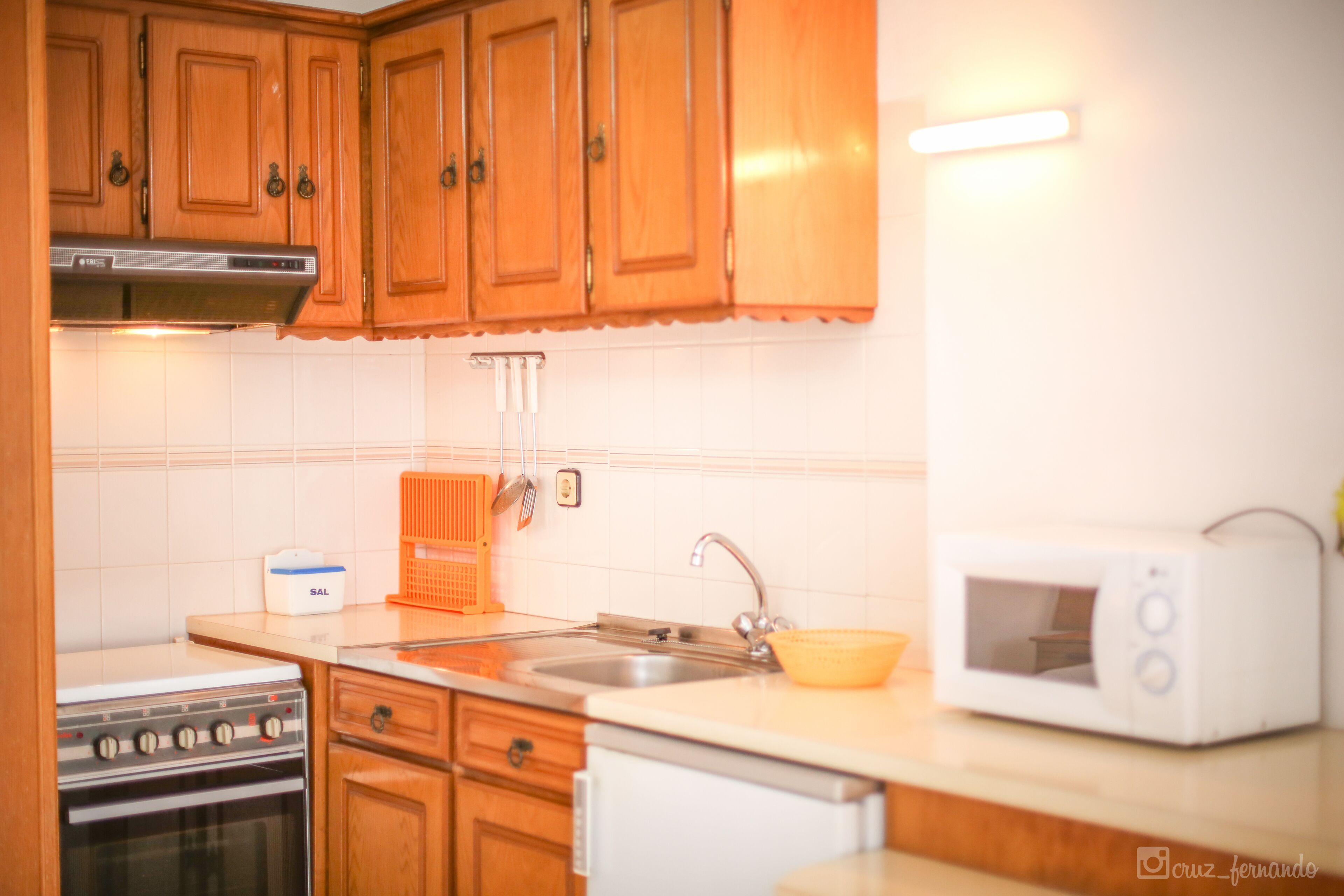 A kitchen with wooden cabinets, a stove, a microwave, and a sink.