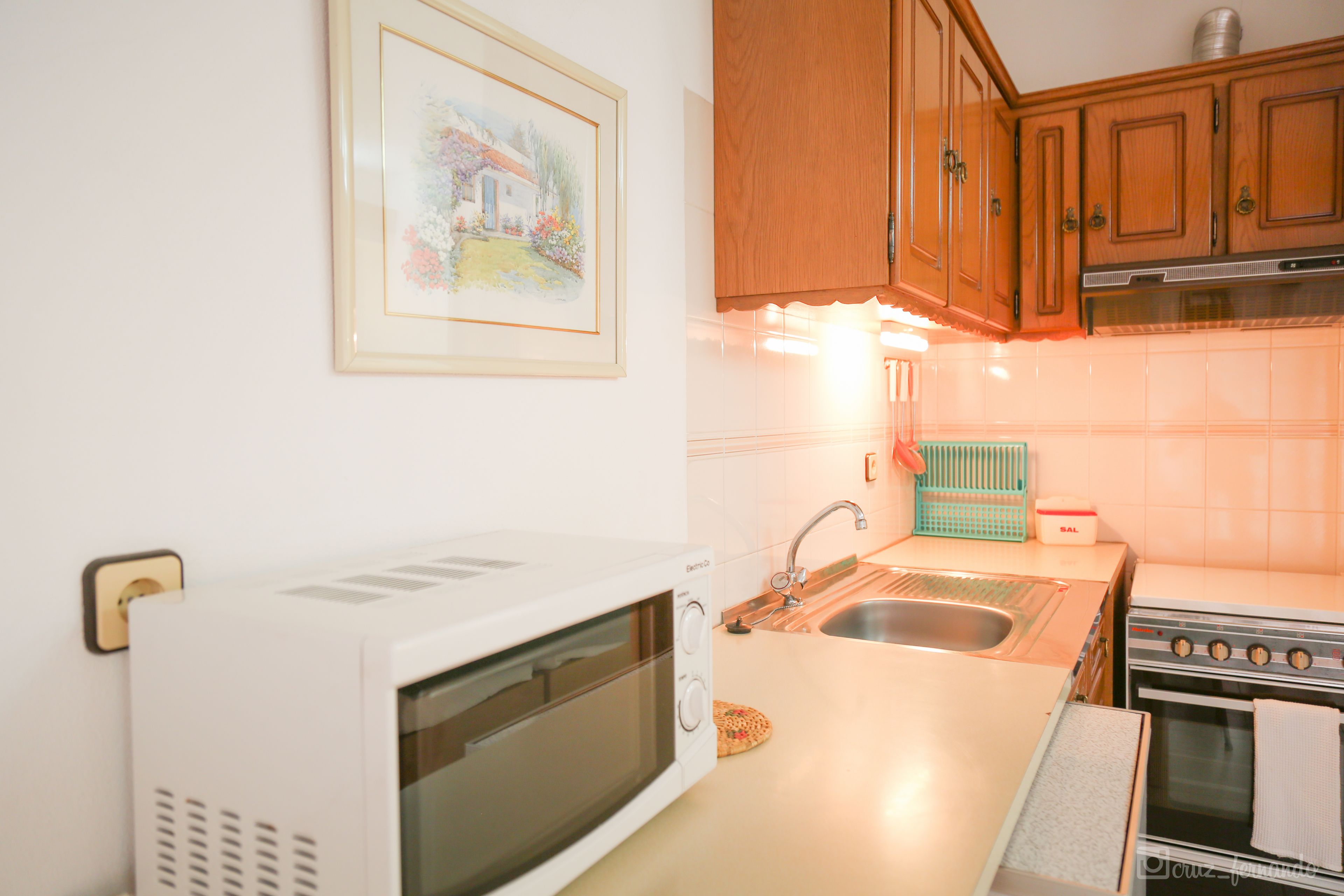 A kitchen with wooden cabinets, a microwave, a sink, and a stove.