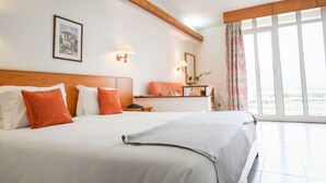 A hotel room with two beds, a wooden headboard, a framed picture on the wall, and a large window with curtains.