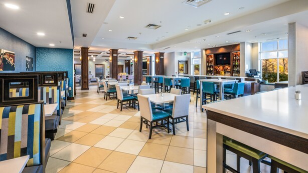 Un restaurante espacioso con techos altos, varias zonas de estar y una barra.