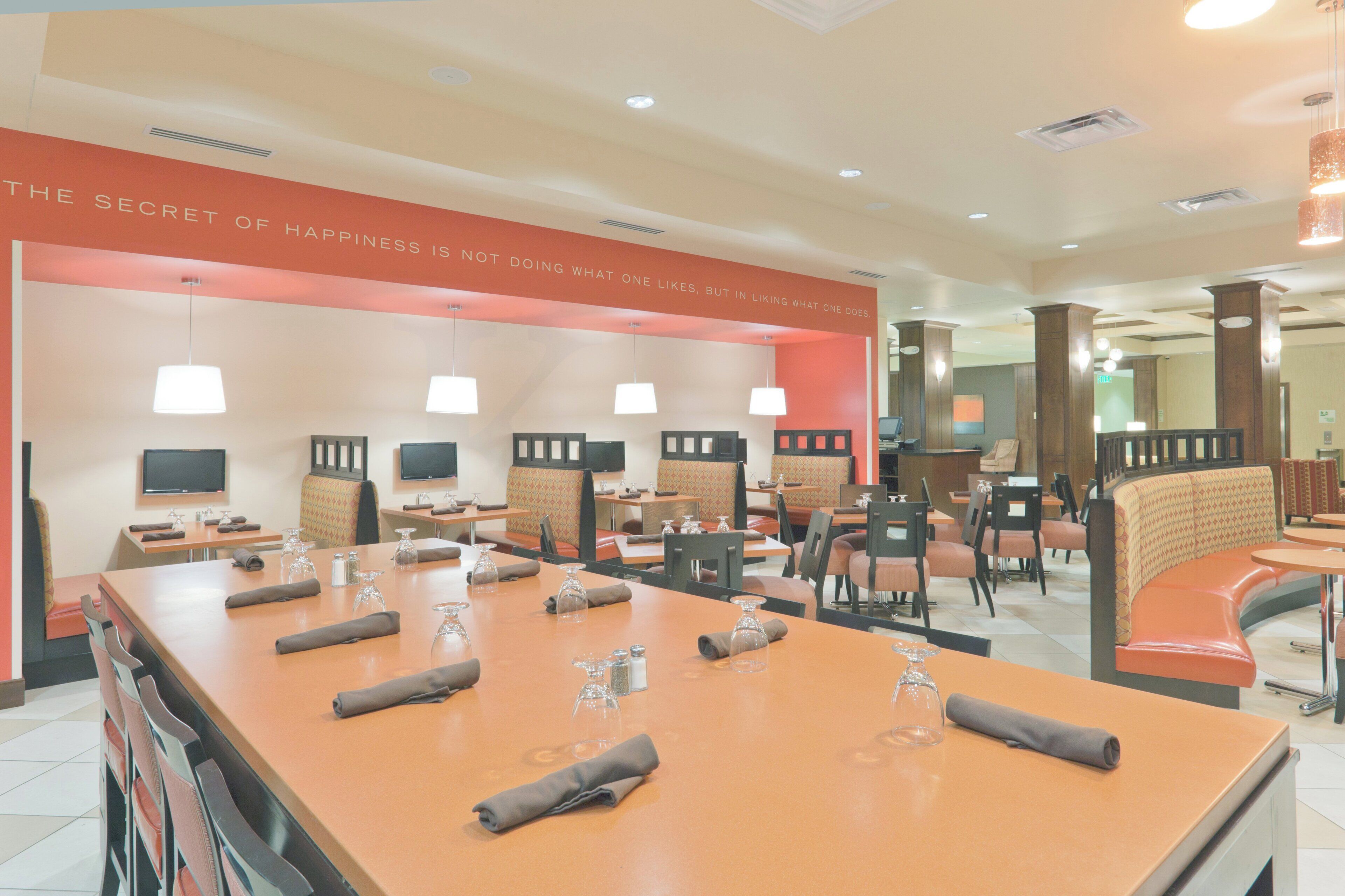 A hotel lobby with a long reception desk, multiple seating areas, and a wall with a motivational quote.