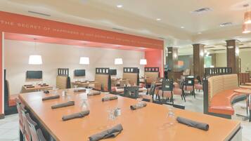 A hotel lobby with a long reception desk, multiple seating areas, and a wall with a motivational quote.