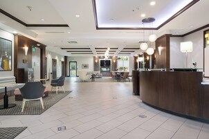 Un vestíbulo de hotel moderno con mostrador de recepción, zona de estar y comedor.