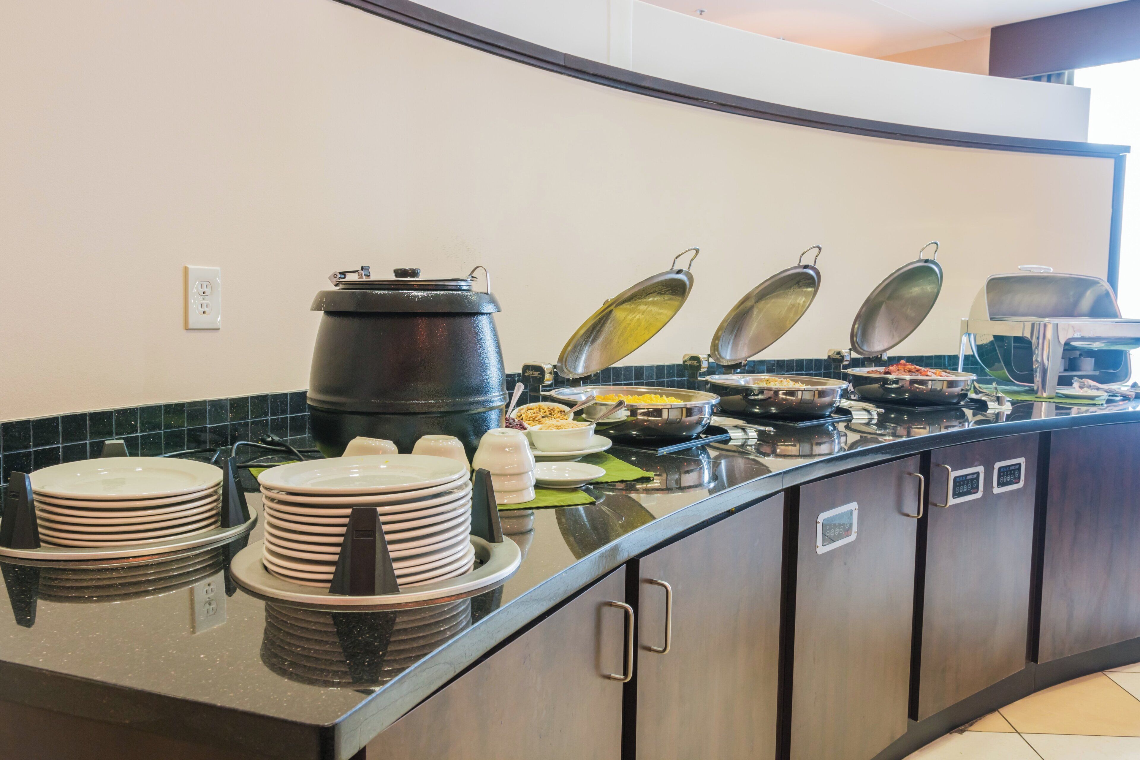 A buffet setup with various food items and serving utensils.