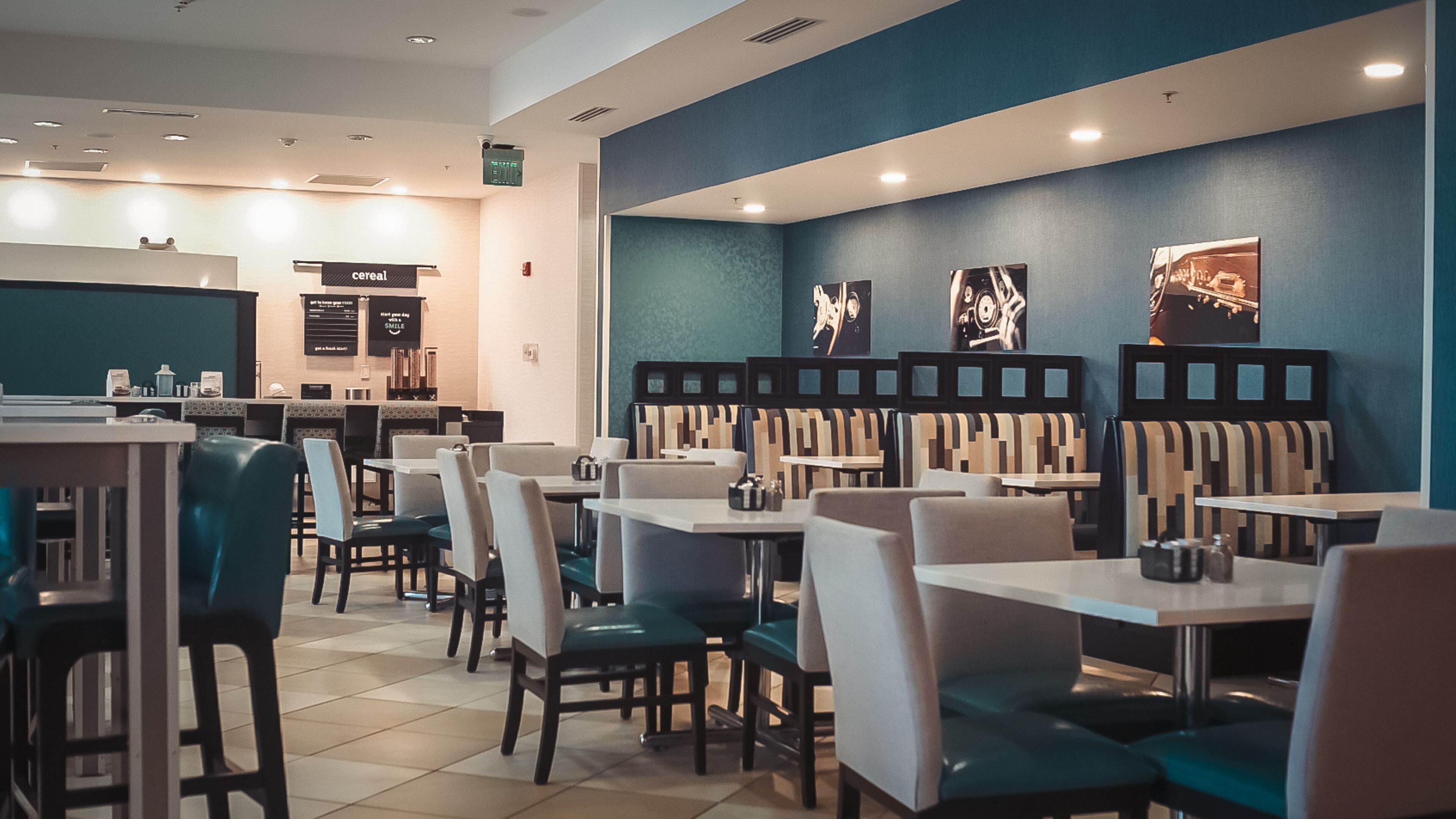 A modern restaurant with booths and tables, a counter with a menu, and a blue accent wall.