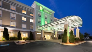 Un hôtel Holiday Inn doté d’une entrée couverte, de plusieurs étages et d’une façade bien éclairée.