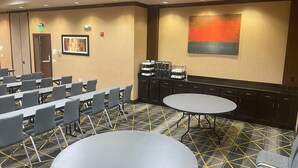 Una sala de conferencias con filas de sillas, una mesa redonda grande y una estación de café.