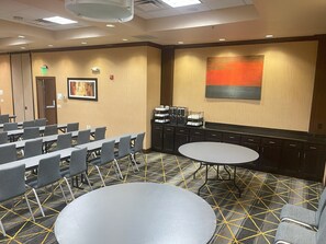 A conference room with rows of chairs, a large round table, and a coffee station.