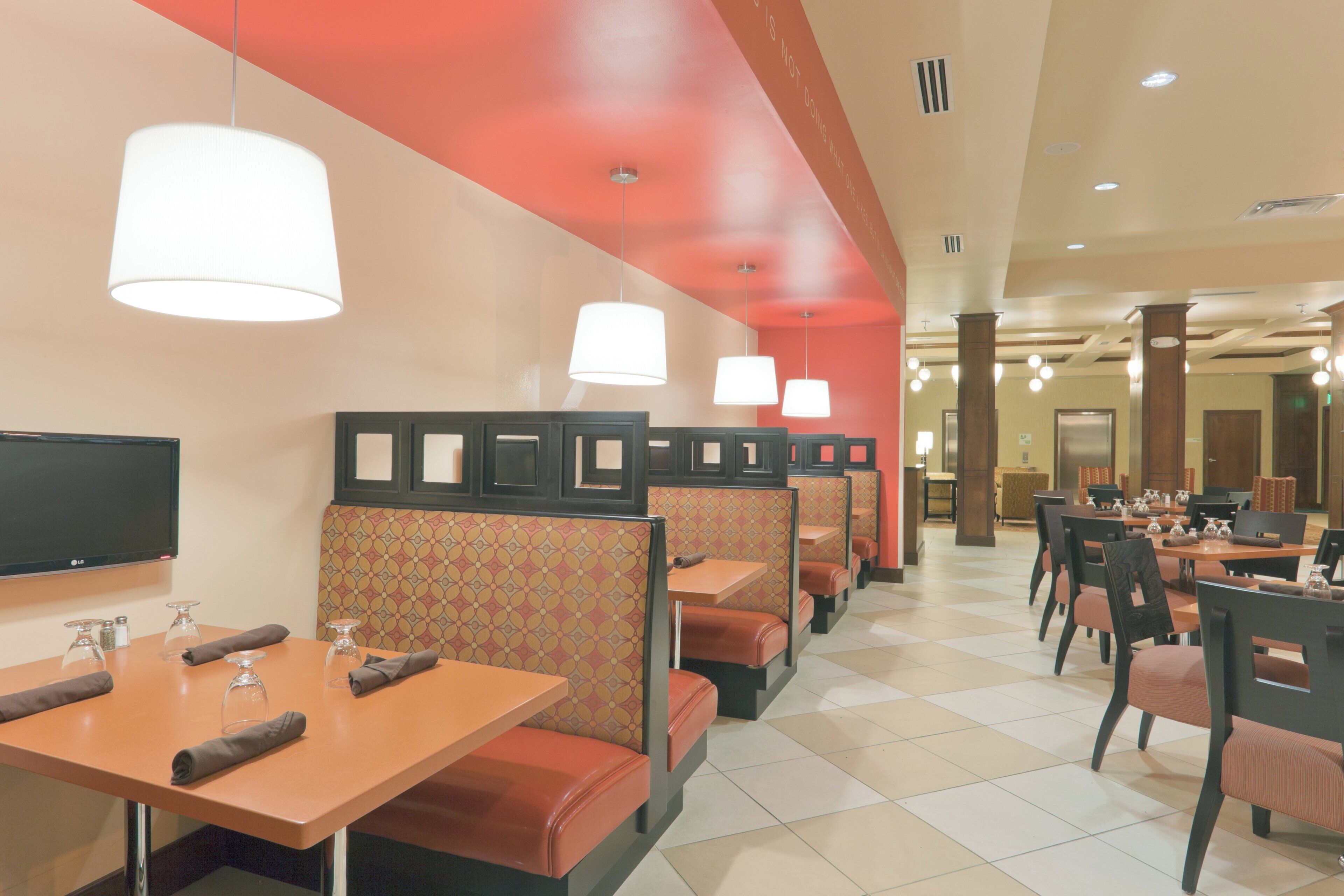 A restaurant with booths and tables, some with glassware and napkins.