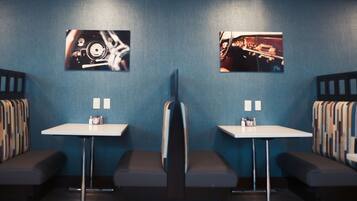 A modern waiting area with two white tables, a bench, and two framed photographs on the wall.