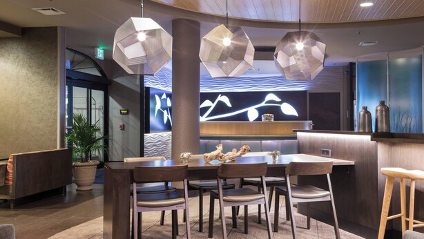 A modern reception area with a wooden reception desk, multiple seating arrangements, and decorative lighting fixtures. - SpringHill Suites by Marriott Quakertown (Quakertown)