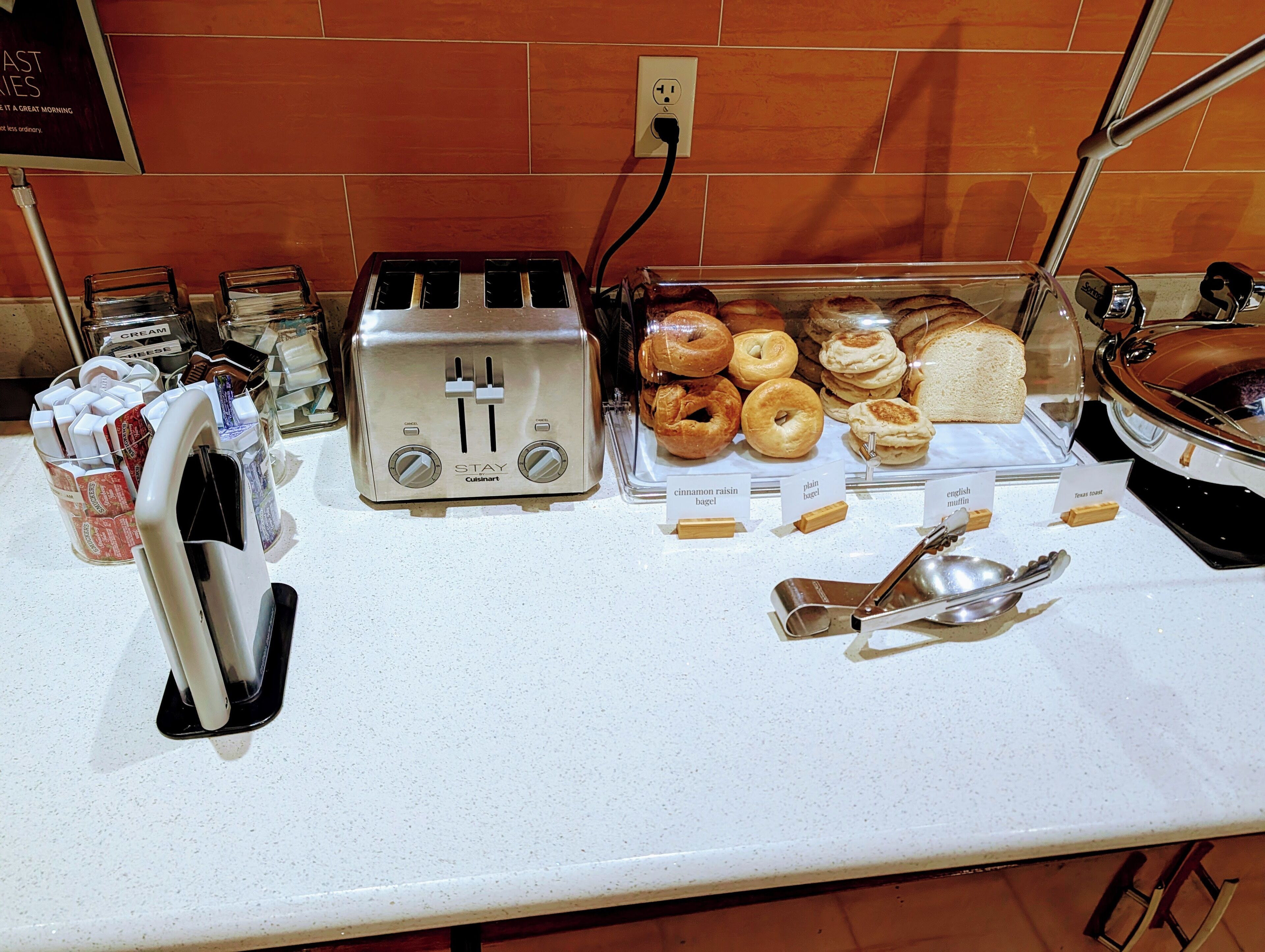 A breakfast buffet with various pastries, a toaster, and condiments.