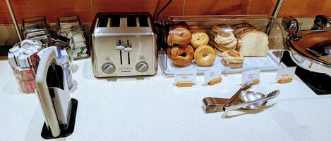 A breakfast buffet with various pastries, a toaster, and condiments.